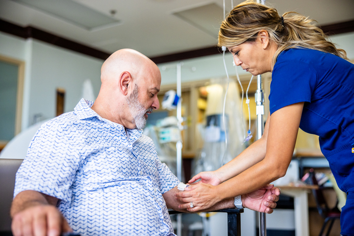 Cost of mesothelioma treatment: nurse administering chemotherapy infusion to cancer patient in hospital setting