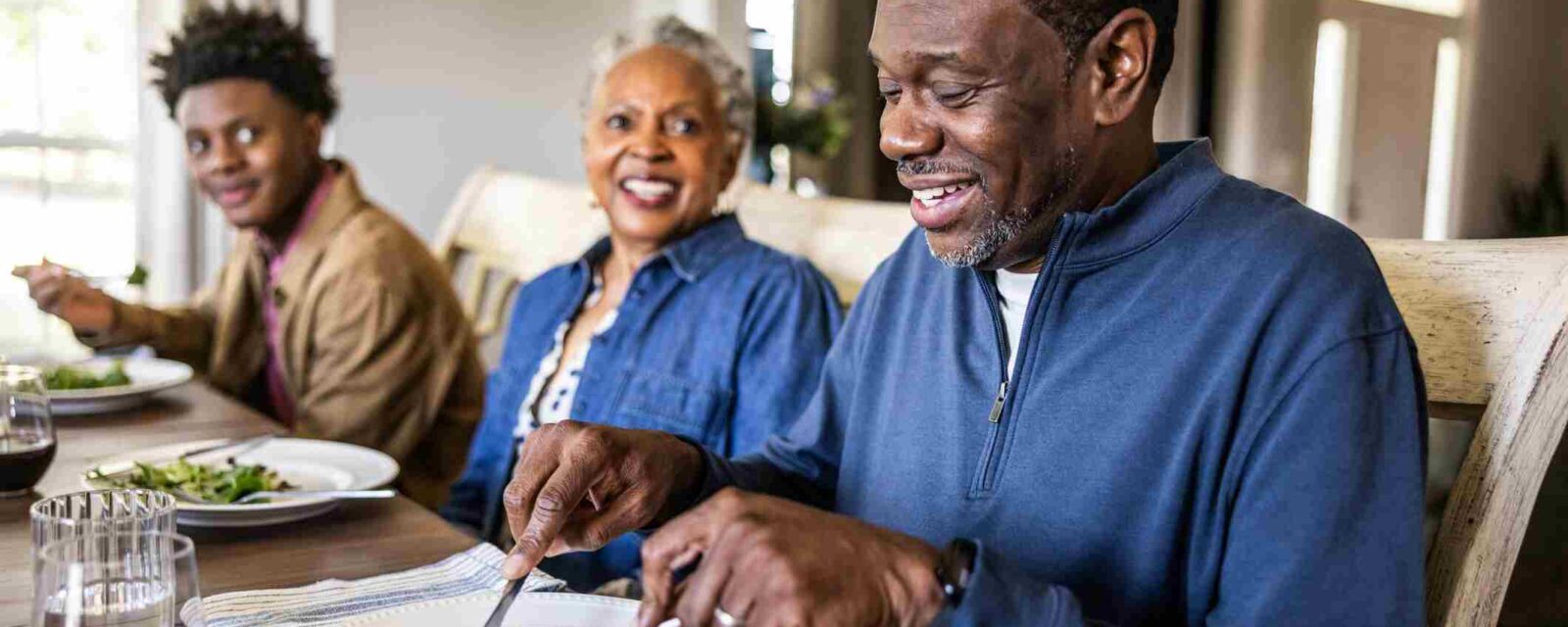 Senior man enjoying mesothelioma diet meal with family at dining table