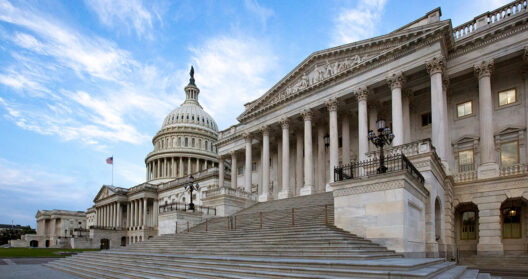 Exterior view of the United States Capitol building in Washington, D.C., featuring the white dome, grand marble steps, and neoclassical columns.