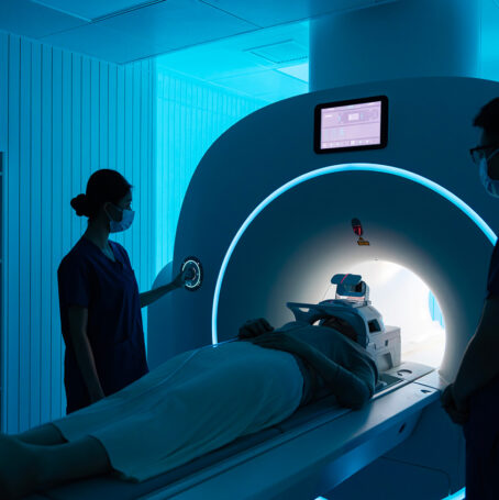 Radiologist getting a patient ready for an MRI mesothelioma test adjusting his position in a dark room.