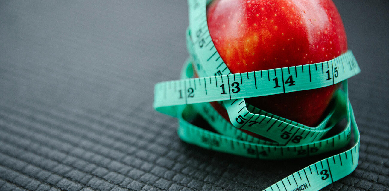 Apple with measuring tape around it, signifying weight loss