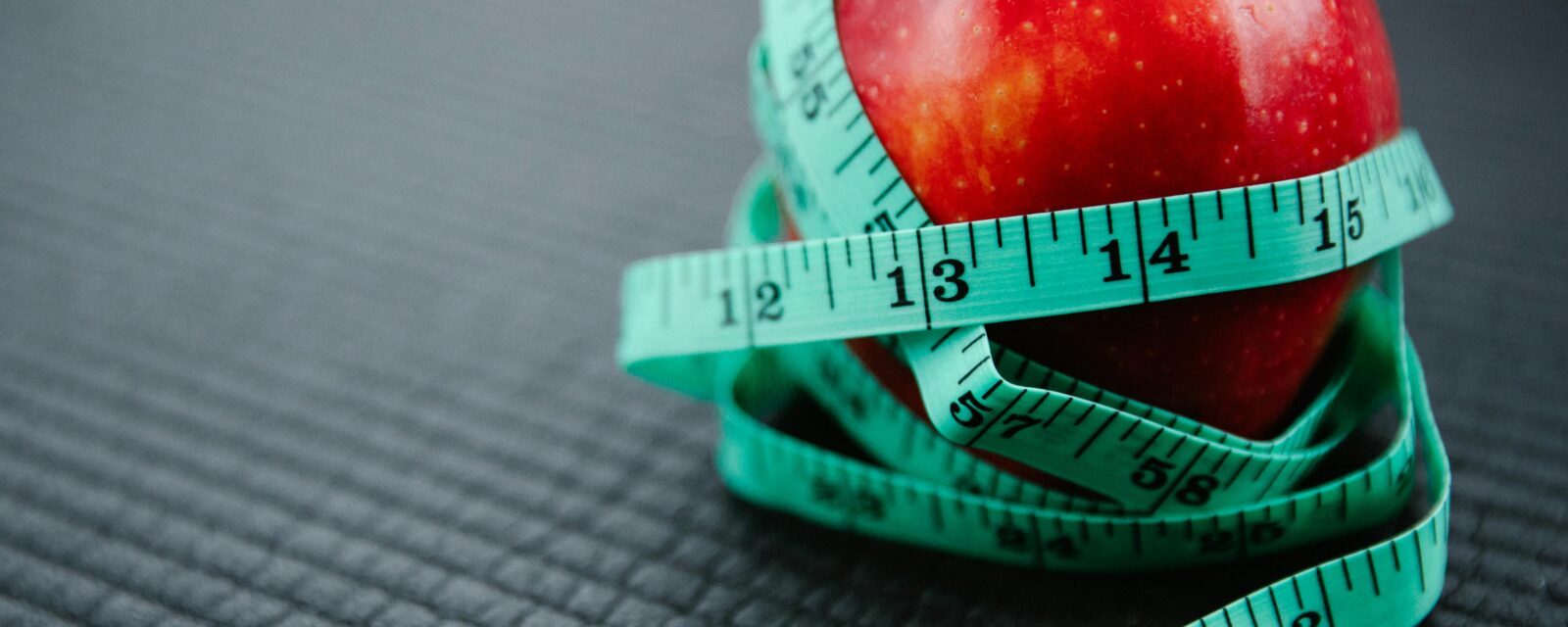 Apple with measuring tape around it, signifying weight loss