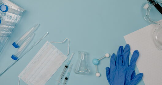 An overhead shot showcasing various laboratory protective gear and equipment on a blue background.